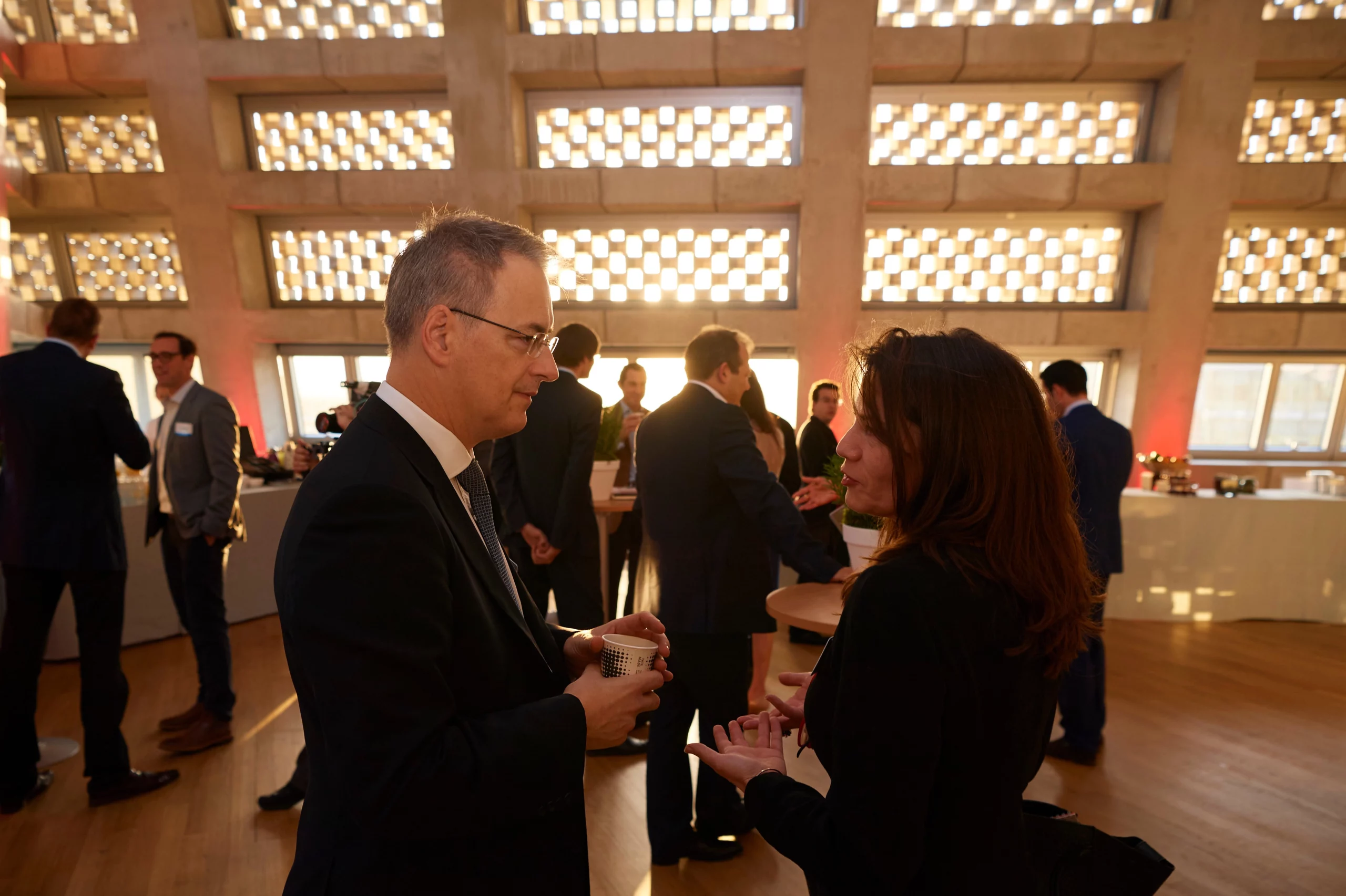 Business professionals engaged in networking and discussions at a MatterXP event, set against a modern architectural background with natural lighting.